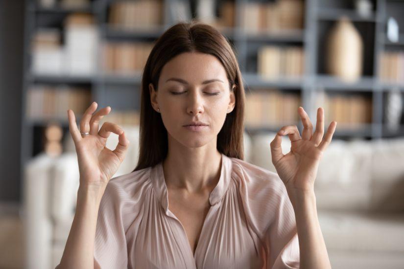 Durch eine feste Morgenroutine kannst du Stress reduzieren. Eine Frau, die meditiert.